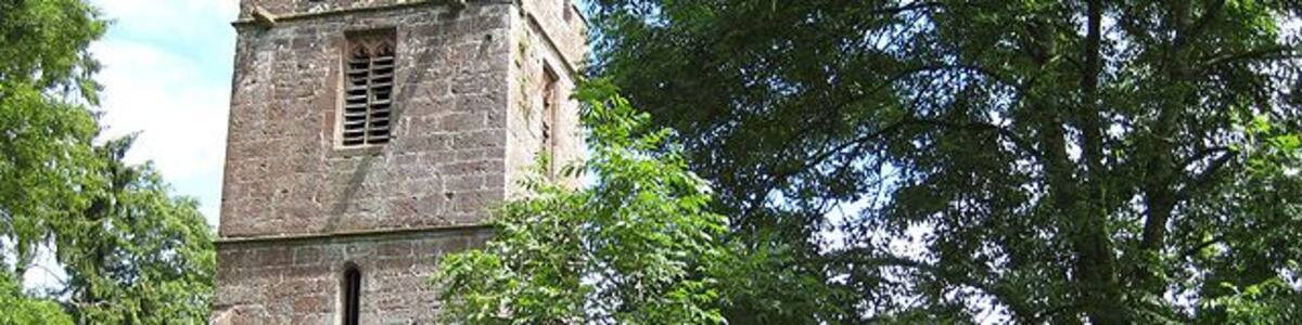 Ruined church of St John the Baptist, near to Llanwarne, Herefordshire, Great Britain. Viewed from the west this shows the tower (with columbarium), south aisle and porch. Abandoned in 1864 due to constant flooding from the nearby Gamber Brook, the roofless church is now in a fairly dangerous condition. Across the road, and built on higher ground, is Christ Church where some artefacts from St John the Baptist's, including an ancient font, have been re-housed.