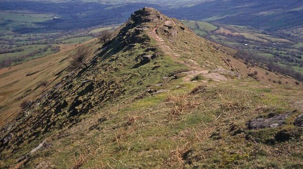 Southern end of the Cat's Back Looking south-east along the ridge with the Olchon valley on the right. The path begins to descend more steeply to the car park after the next rock outcrop. Beyond and just to the right of the outcrop, the lane leading up to the car park can be seen skirting around Little Black Hill. Superb views over Herefordshire from the only Black Mountains ridge wholly inside England.