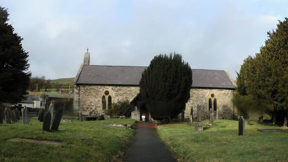 A church surrounded by a cemetery with gravestones and trees.