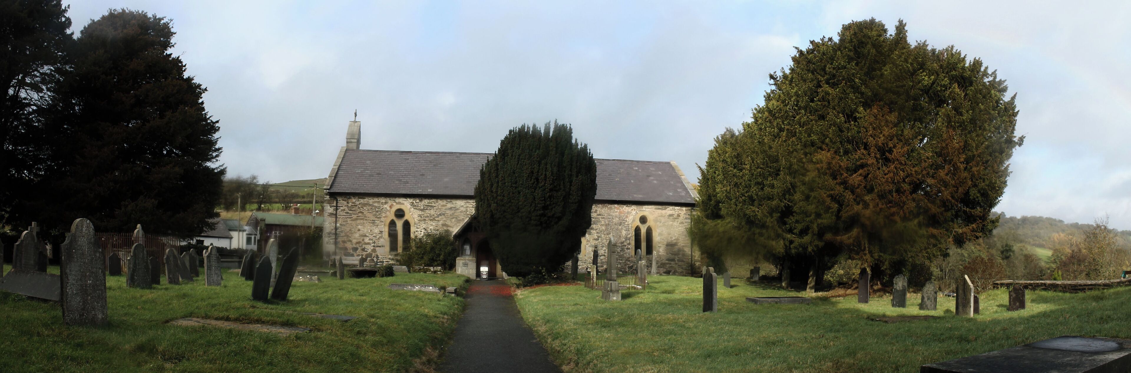 A church surrounded by a cemetery with gravestones and trees.