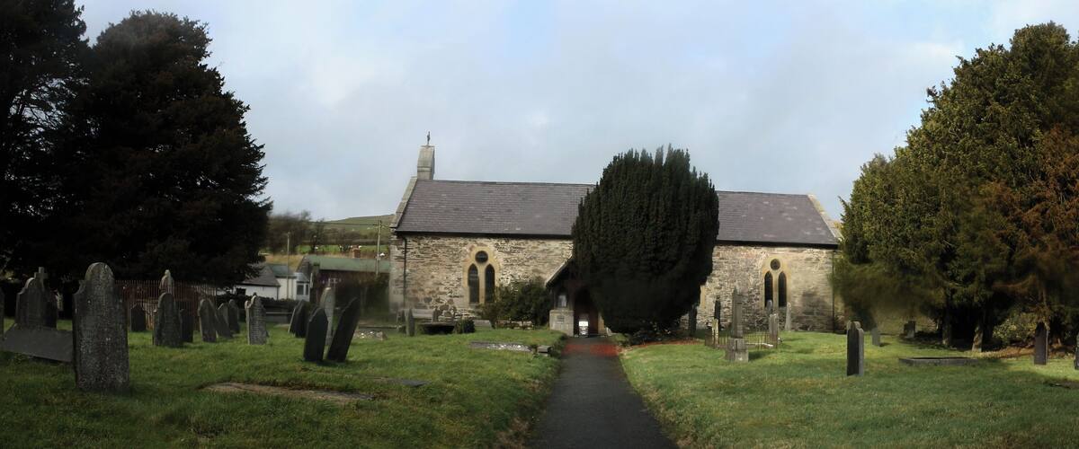 A church surrounded by a cemetery with gravestones and trees.