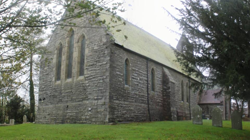 A stone church with a steep roof and arched windows.