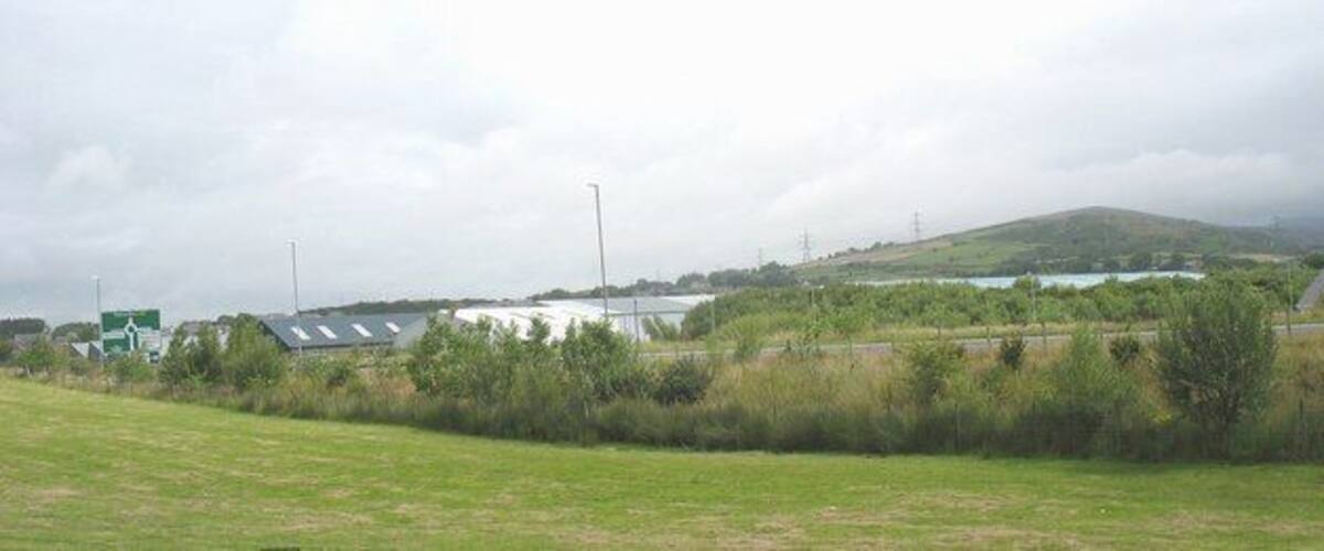 A grassy field with a building and a road in the background.