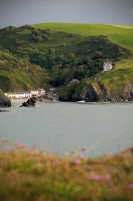 A coastal landscape with a hill, a building, and a body of water.