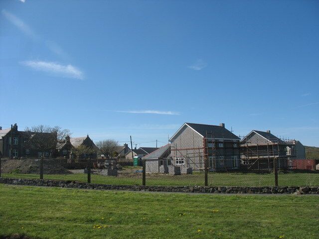 A rural landscape with houses, a fenced area, and a clear blue sky.