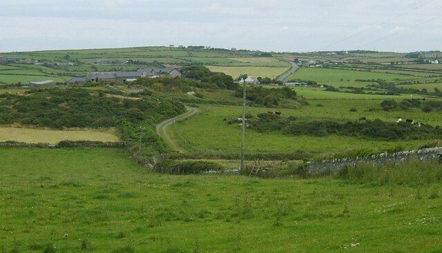 A rural landscape with rolling hills, a winding road, and scattered houses.