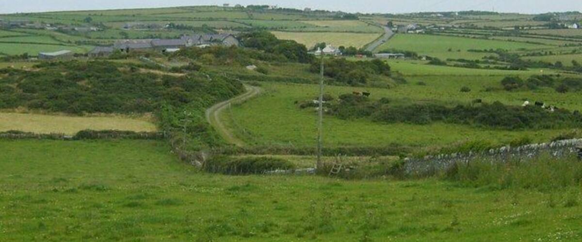 A rural landscape with rolling hills, a winding road, and scattered houses.