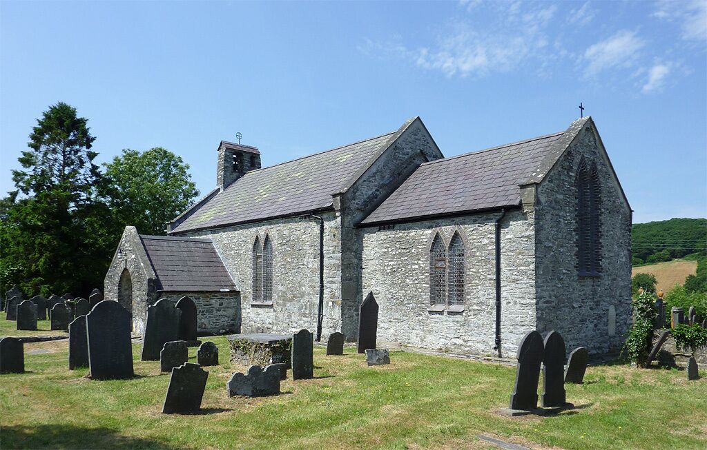 A stone church with a steeple and a graveyard with headstones.