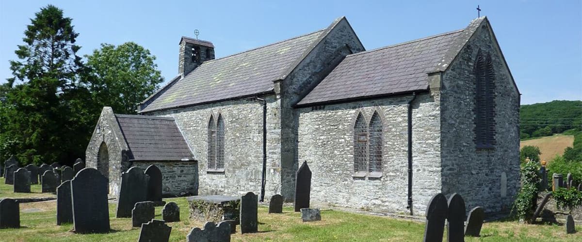 A stone church with a steeple and a graveyard with headstones.