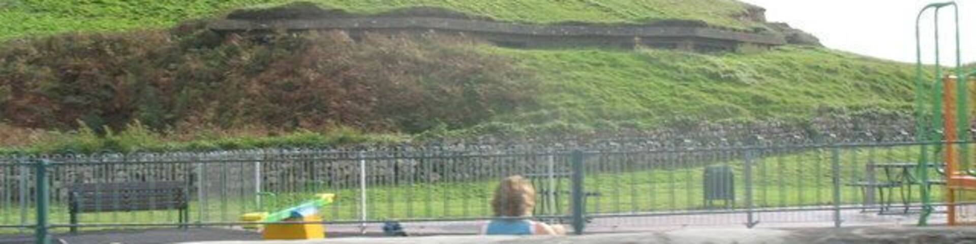 A Machine Gun Nest in an Iron Age Fort. This large pill box was constructed within the northern slope of this important Iron Age fort as part of the elaborate system of defences surrounding RAF Llandwrog. The beaches were also heavily mined. The railed off area in the foreground is a kiddies playground.