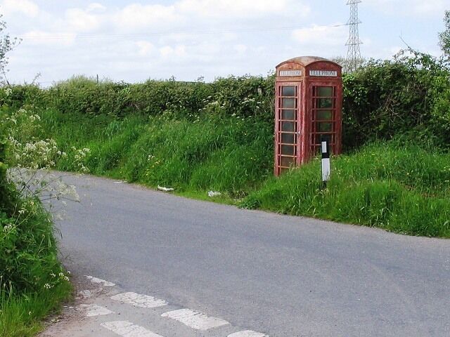 Red phone box near Constant Farm, Llandyfaelog. The faded and flaking red paint on this poor old phone box looks older than the modern phone inside.
