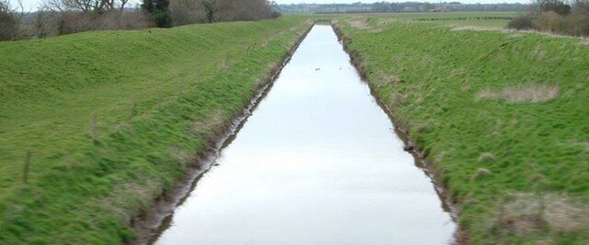 A narrow water channel flanked by grassy banks.