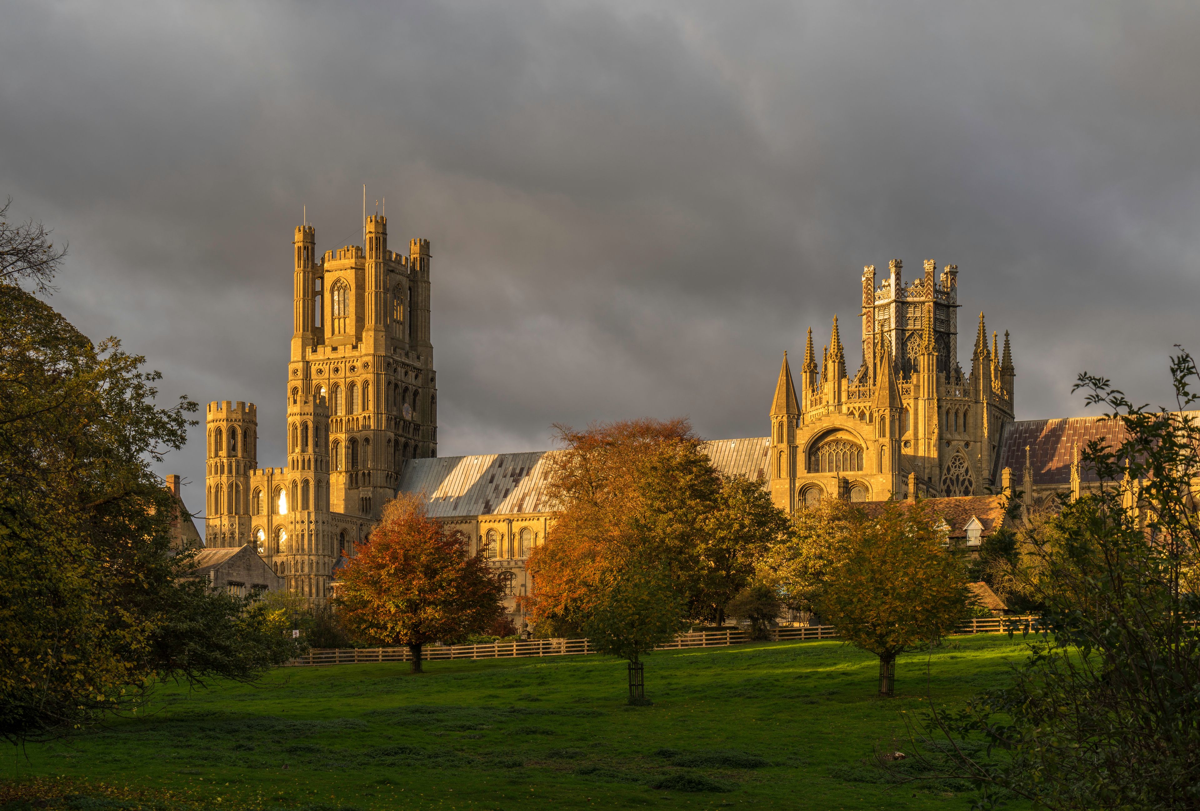 A historic cathedral with tall spires and intricate architecture, surrounded by a grassy field and trees.