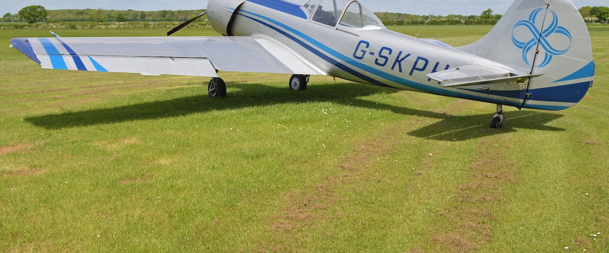 A small aircraft with registration G-SKP on a grassy field.