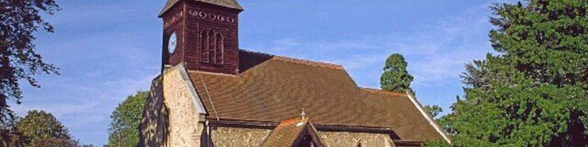 Una iglesia con campanario y torre del reloj, rodeada por un cementerio con lápidas.