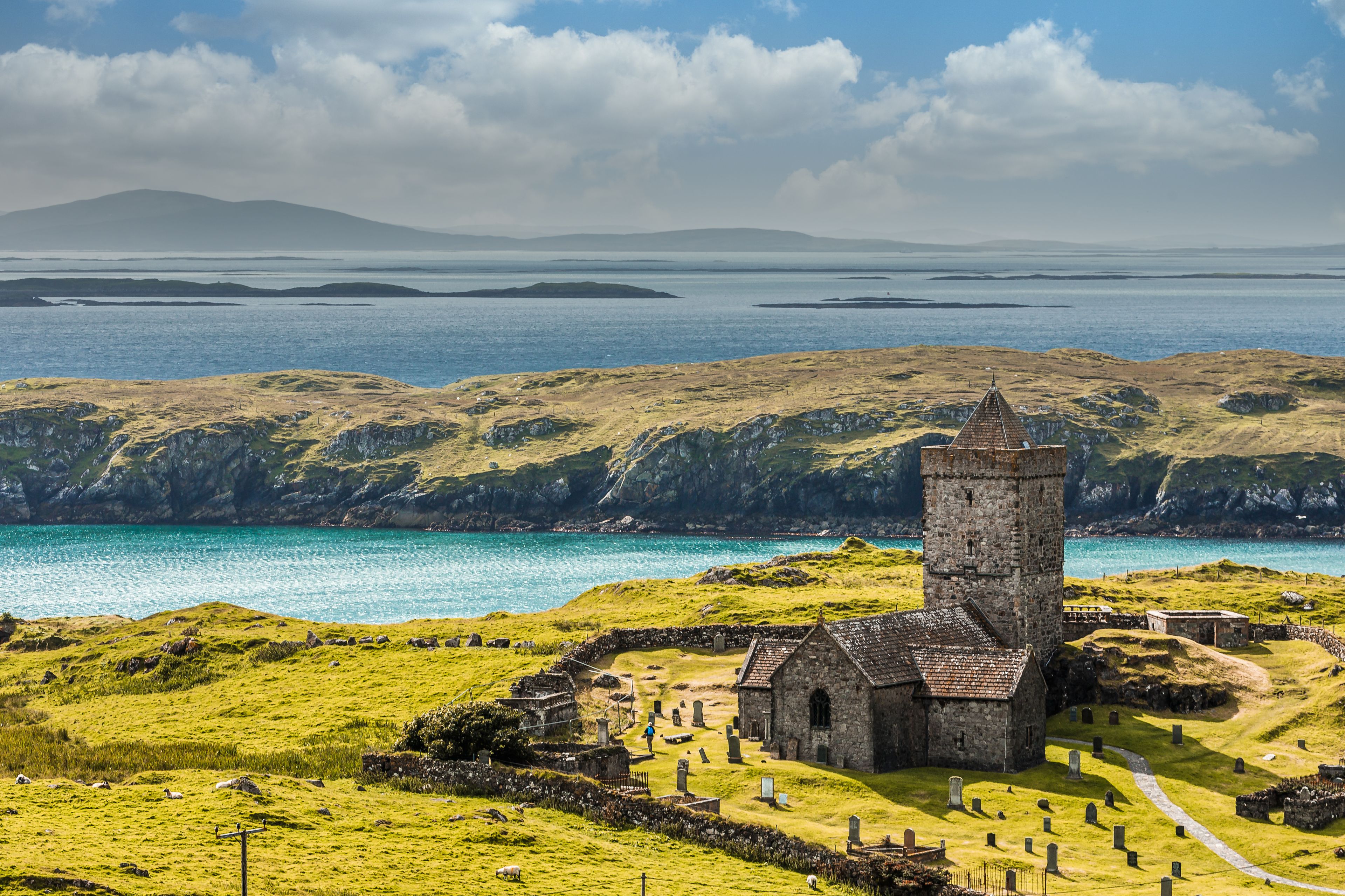 Eine Küstenlandschaft mit einer Kirche, grasbewachsenen Hügeln und freiem Blick auf das Meer.