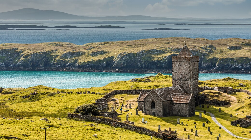 Eine Küstenlandschaft mit einer Kirche, grasbewachsenen Hügeln und freiem Blick auf das Meer.
