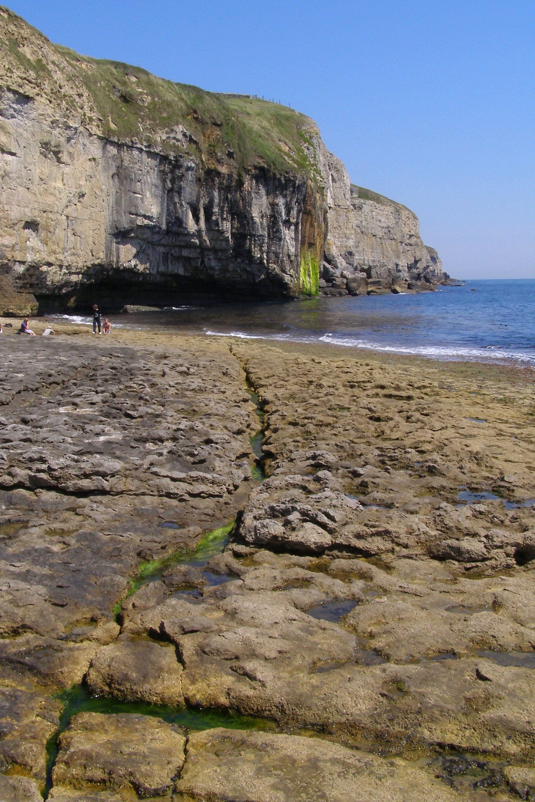 Una playa rocosa con un acantilado al fondo.