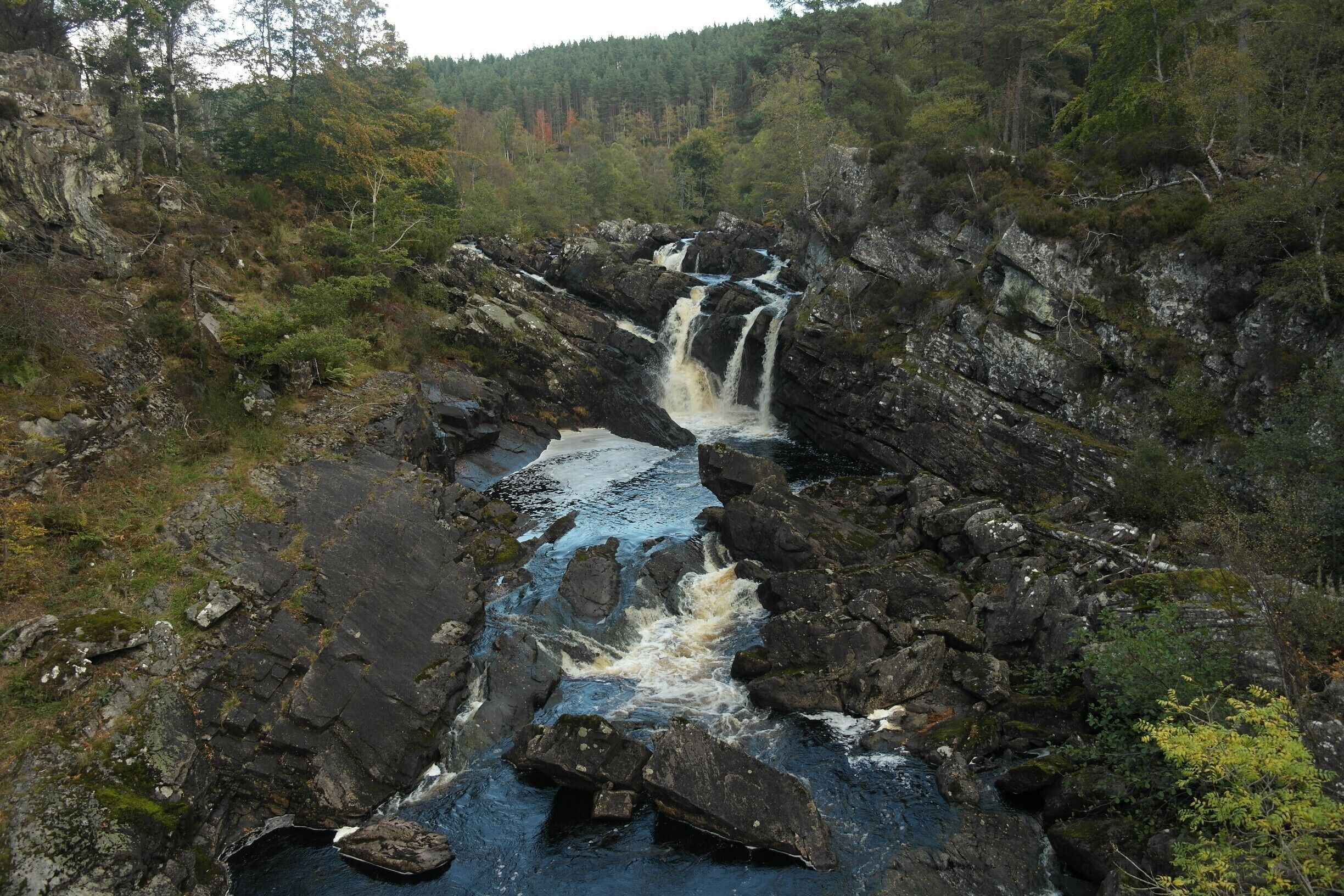 A waterfall cascading over rocks in a forested area.