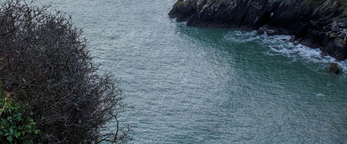 A coastal landscape with rocky cliffs and calm sea.