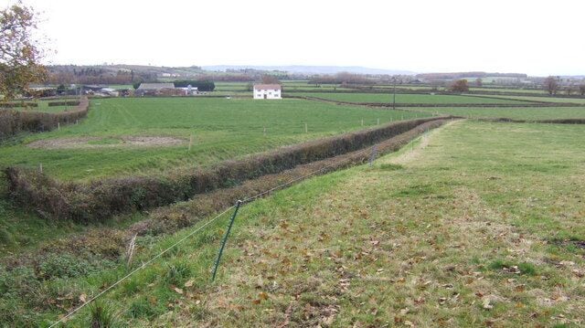 A rural landscape with fields, a white building, and a narrow path.