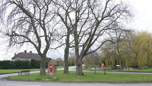 Village Green, Little Kineton. Looking south across the small village green with three trees and a victorian post box 1779449. The village pond 1779420 is visible behind the green on the right.