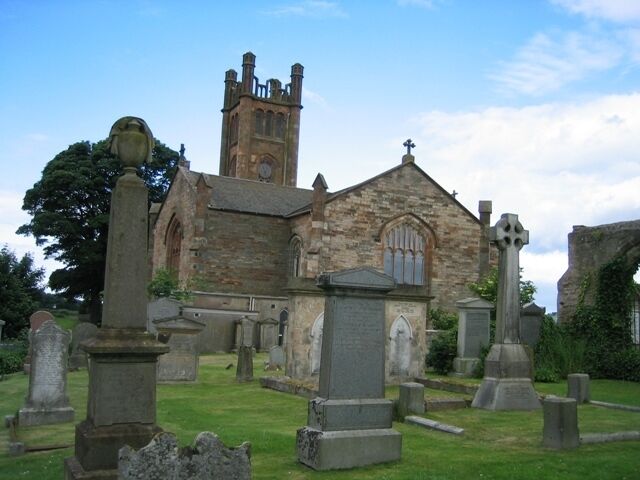 A historic church with a tall tower and stone gravestones in the foreground.