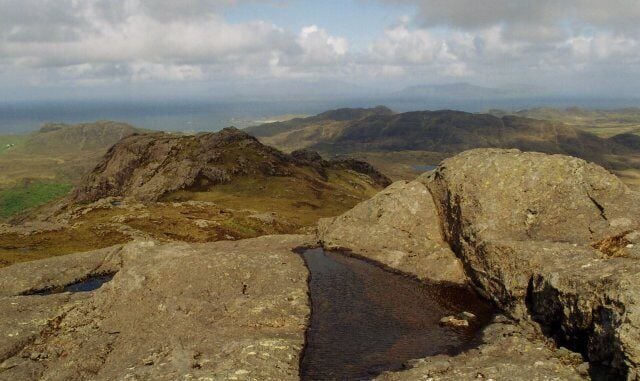 Beinn na Seilg. Beyond the summit of Beinn na Seilg lie the Small Isles of Eigg and Rum and, almost invisible in the mist, the Isle of Skye.