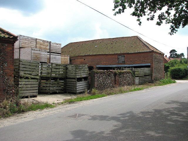 A rural road with a brick building and wooden pallets.