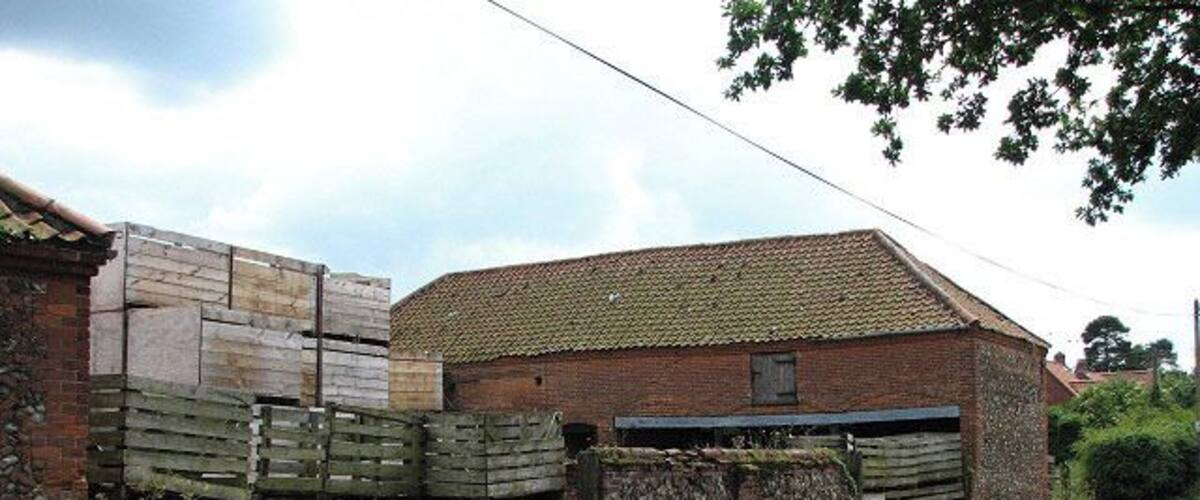 A rural road with a brick building and wooden pallets.
