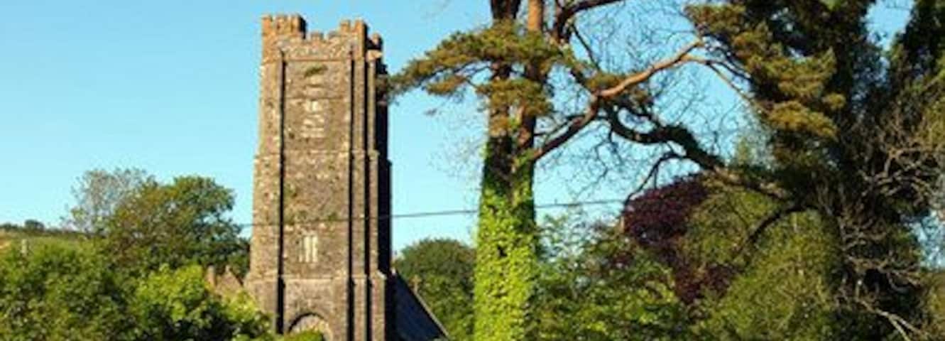 Road junction in Kentisbury, Devon, with the tower of St Thomas's parish church in the background