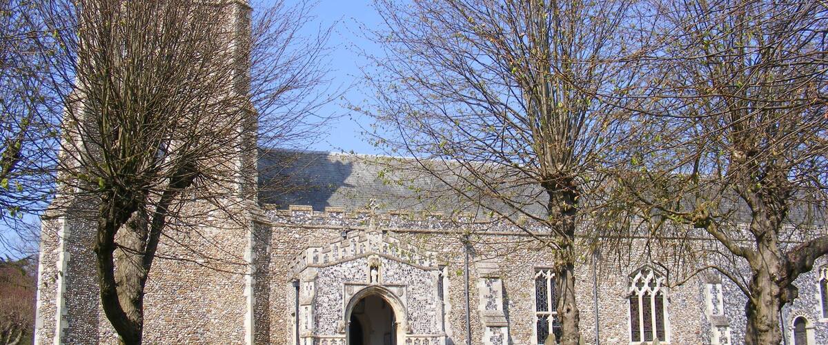 A historic stone church with a tall tower, arched entrance, and Gothic windows.