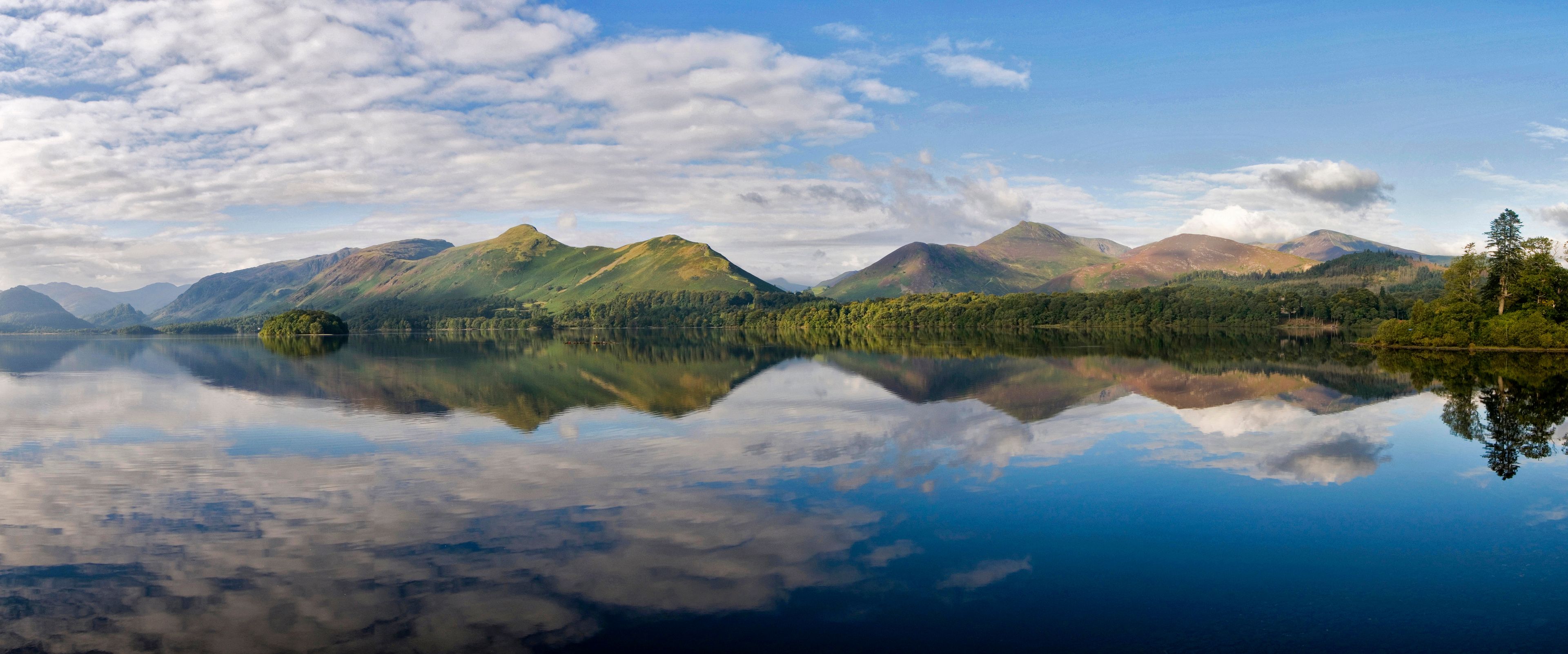 A calm lake reflecting mountains and a clear sky.