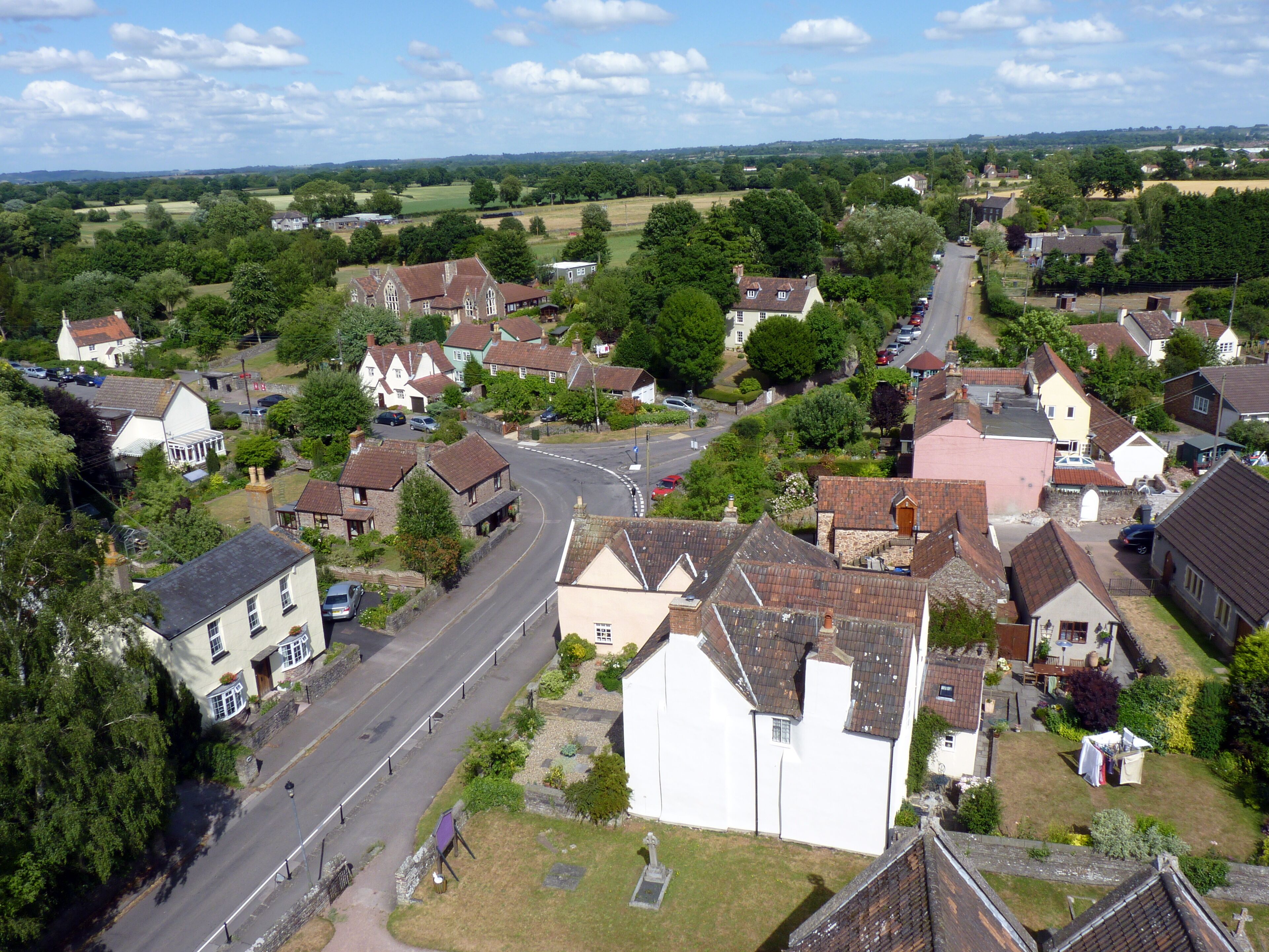 A village with a main road, houses, and surrounding greenery.