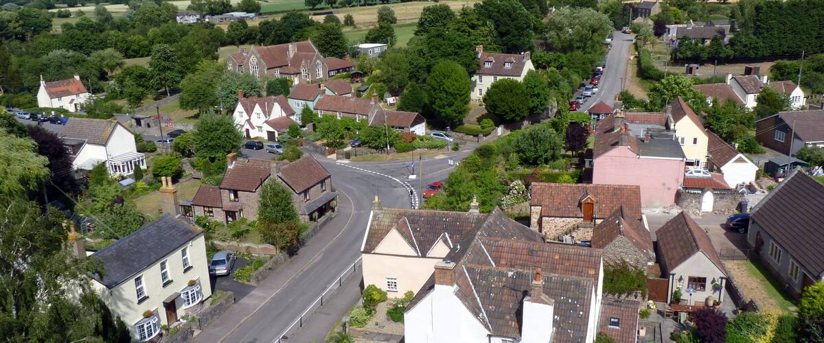 A village with a main road, houses, and surrounding greenery.