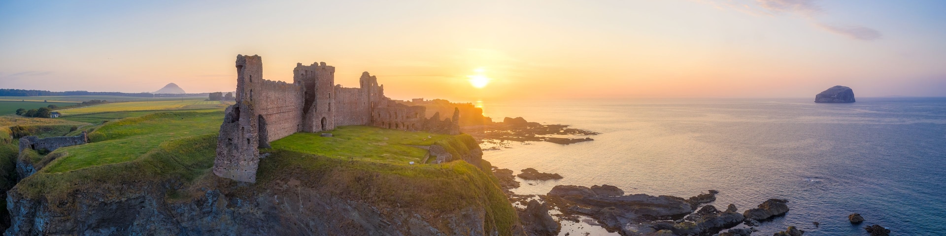 Un castillo costero al atardecer con cielo despejado y mar tranquilo.