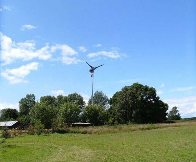Una turbina eólica en un paisaje rural con árboles y cielo despejado.