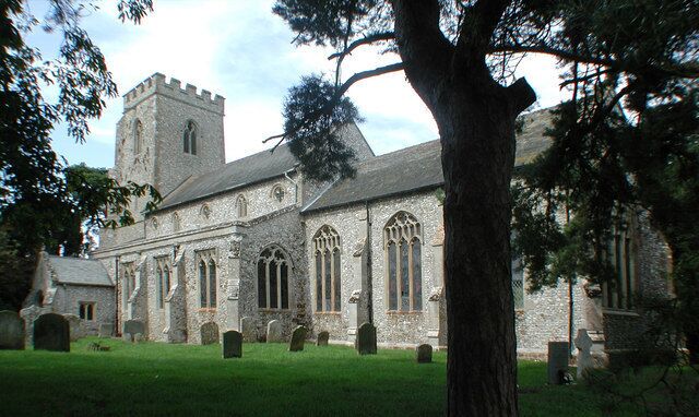 A historic stone church with a tower and arched windows, surrounded by a cemetery.