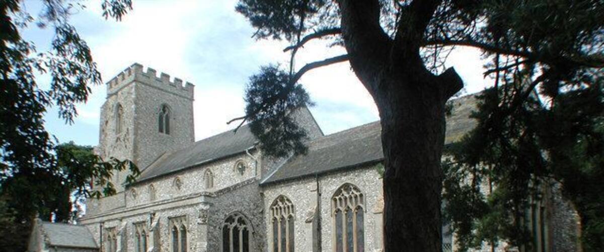 A historic stone church with a tower and arched windows, surrounded by a cemetery.