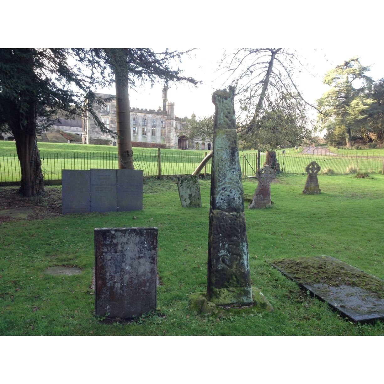 A cemetery with ancient stone crosses and a historic building in the background.