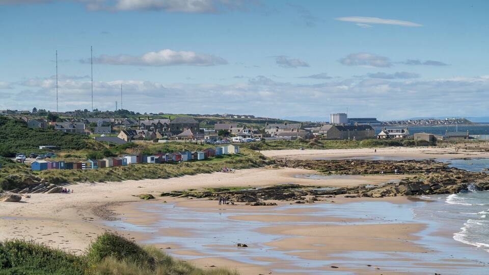 A coastal town with sandy beaches, rocky outcrops, and colorful beach huts.