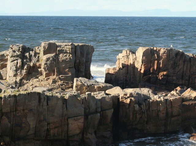 Una costa rocosa con olas rompiendo contra las rocas.