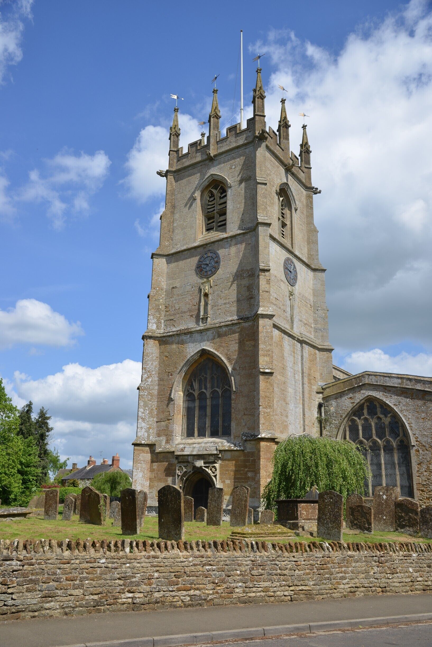A historic church with a tall tower, arched windows, and a stone wall with headstones.