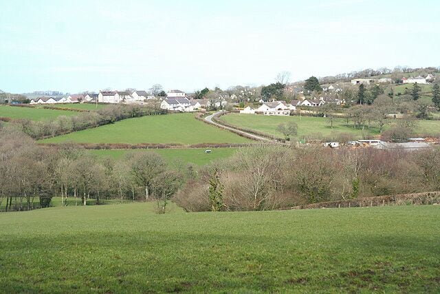 Highampton: towards the village The hedge running horizontally across the field below the village indicates the course of the Great Torrington - Halwill Junction Light Railway which has more recently become a cycle track linking Highampton with Black Torrington