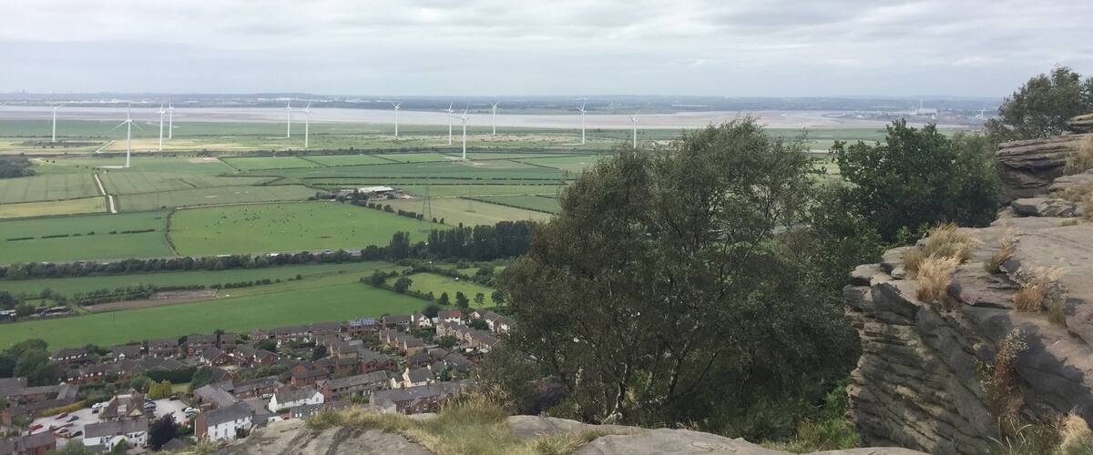 A rural landscape with wind turbines, green fields, and a small village.