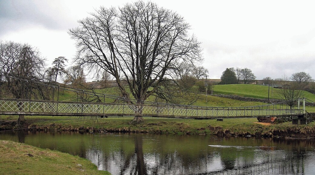 This is a wrapped steel-cable suspension bridge over the River Wharfe. The bridge was built in 1885 by local blacksmith William Bell, and paid for by public subscription. Made of recycled materials, it originally had a central supporting pier, that was removed when the span was raised in 1937 after being damaged in a heavy flood.