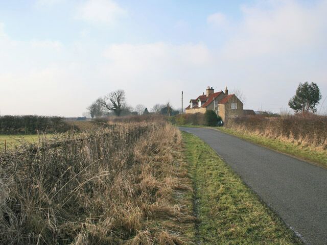 Road between Gorse Lane and Stroxton. Lodge Farm East Cottage has commanding views across the Lincolnshire countryside. Lodge Farm is behind the trees in the centre of the photograph.