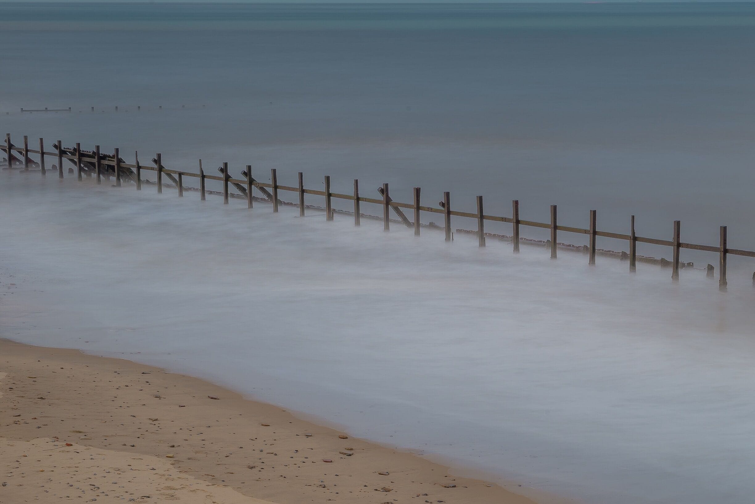 Happisburgh battered sea groynes

The story of the village is inseparably linked with the sea. For residents of Happisburgh, and for hundreds who visit each year, the sea represents many different things: a source of livelihood; a place of recreation and fun; a sight to gaze at and wonder over; a worrying, unpredictable, dangerous and potentially destructive power.

Happisburgh has lost land to the sea throughout the centuries. The rate of erosion has been erratic - at times large areas have disappeared overnight, and at others the cliff has remained virtually the same for some years.

You can walk for miles on this beach, as far as Sea Palling if you wanted to. At the end of the south beach you reach Cart Gap, which is where the lifeboat is now stationed, having previously been at Happisburgh beach before all the coastal erosion.

#seascape #beach #sea #waves #longexposure #nautical #ocean #shore #seaside #coastal #norfolk #england #britain #UK