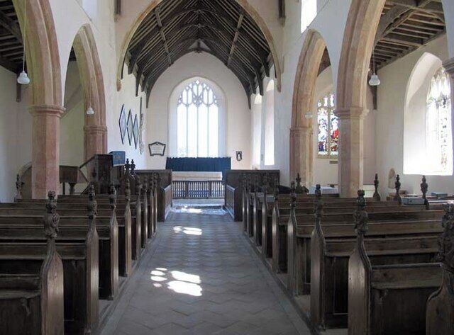 An interior of a church with wooden pews, arched ceilings, and stained glass windows.