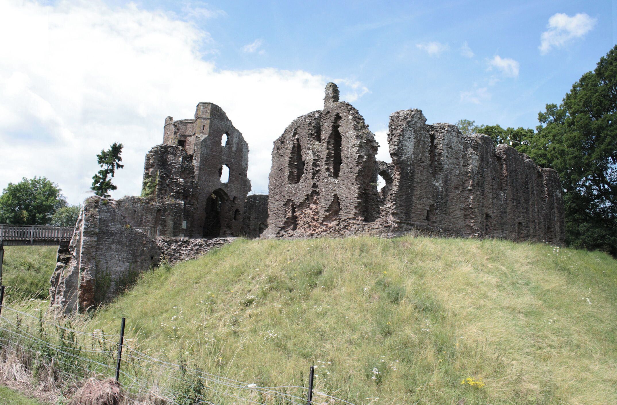 A historic stone ruin with arches and a bridge in the background.
